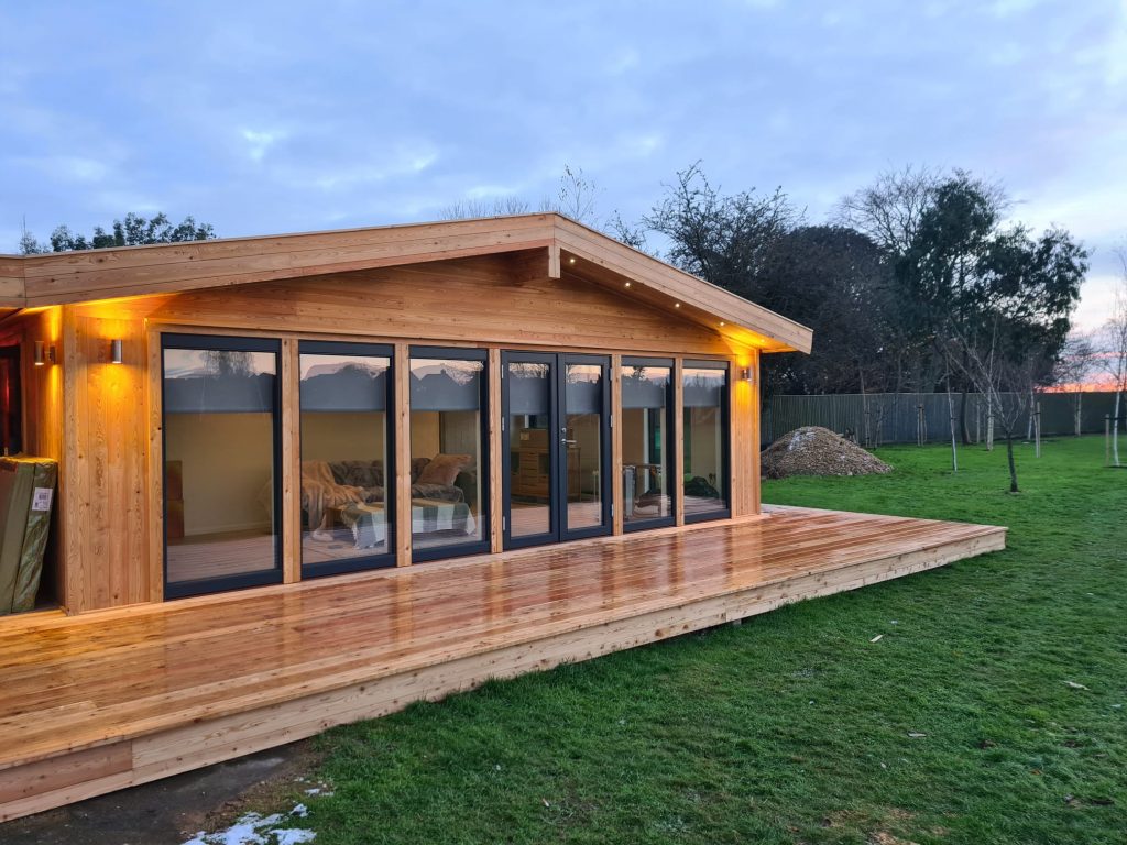 A large timber garden room with pitched roof featuring 5 large windows and a set of double doors