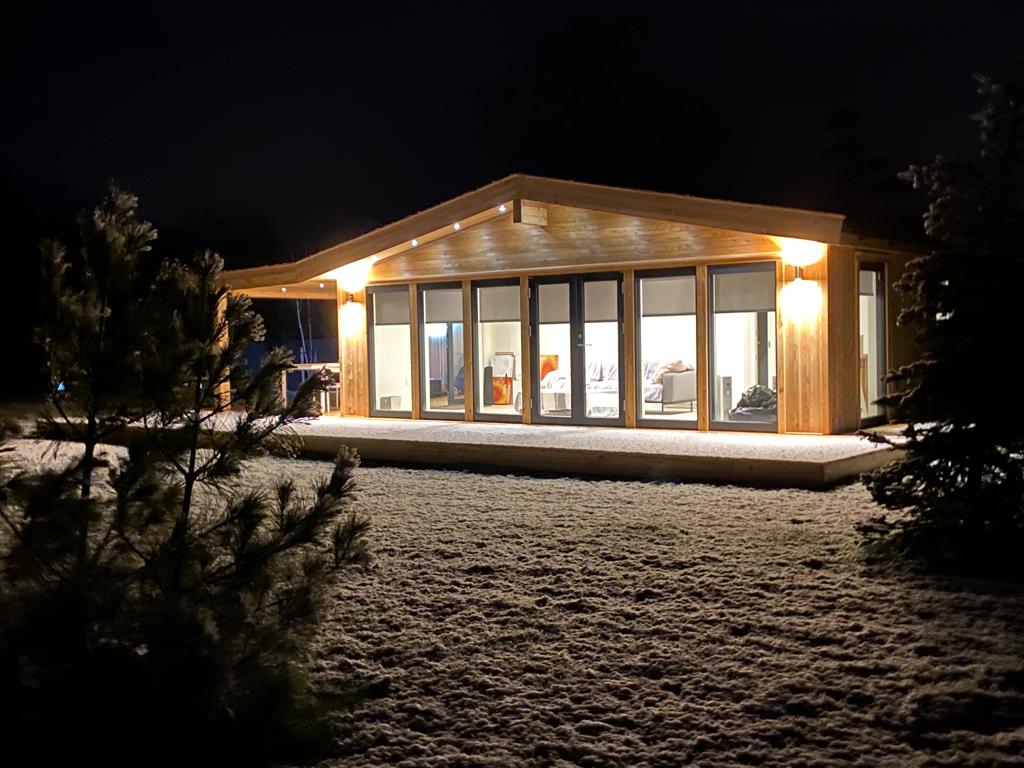 Large timber garden room in a night time setting with snow on the ground